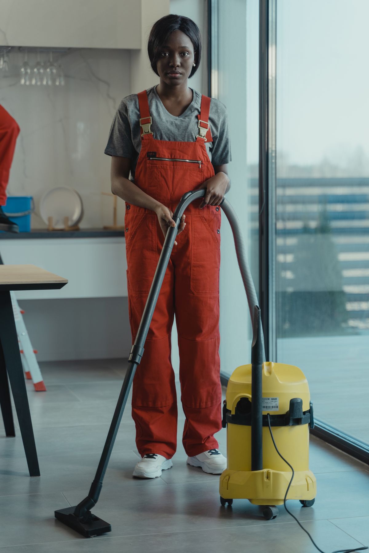 Une professionnelle du nettoyage Kleen-Net, femme africaine en tenue de travail, passe l'aspirateur avec énergie